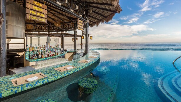Piscina infinita com área de bar, cardápio de bebidas e vista para o oceano.