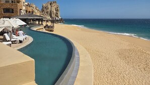 Um resort à beira-mar com piscina, espreguiçadeiras e um edifício com varandas.