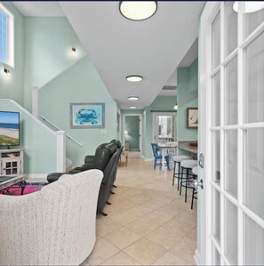 A living room with a sofa, a TV, and a staircase leading to another room. - Spacious 4-bedroom house in perfect Surfside Beach with AC (Surfside Beach)