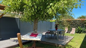 A wooden swing chair, a small table with chairs, and a potted plant in a backyard. - Gite la Pinassotte - GUJAN-MESTRAS (GUJAN-MESTRAS)