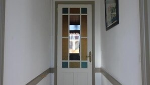 A hallway with a door featuring a window, a framed picture on the wall, and a tiled floor. - Gite la Pinassotte - GUJAN-MESTRAS (GUJAN-MESTRAS)