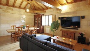 Un interno in legno con zona pranzo, divano, televisione e una pianta.