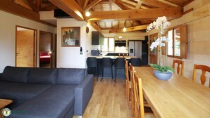 Un'ampia zona giorno con divano, tavolo da pranzo, sedie e una cucina sullo sfondo.