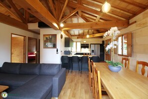 A spacious living area with a sofa, dining table, chairs, and a kitchen in the background. - La Ruche - CAMBES - Gîte (CAMBES)