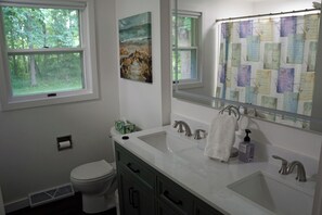 Une salle de bain avec des toilettes, deux lavabos, un miroir et une fenêtre.