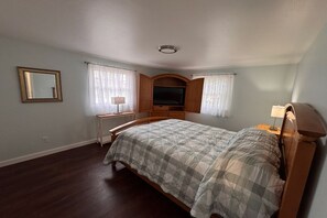 Une chambre à coucher avec un lit, un bureau, une télévision et un miroir.
