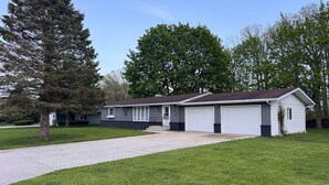 Einbungalow mit Garage, Vorgarten und einem großen Baum links.