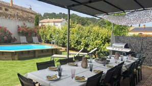 Zona d'exterior per dinar amb piscina, una barbacoa i vistes a l'entorn, el jardí i els edificis.