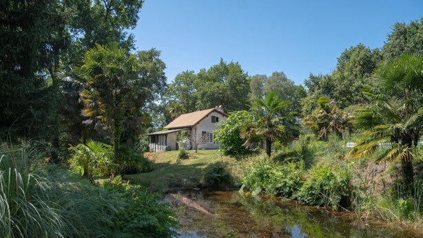 A house surrounded by lush greenery and a small pond. - Gîte du Pitchouret - BELIN BELIET (BELIN BELIET)