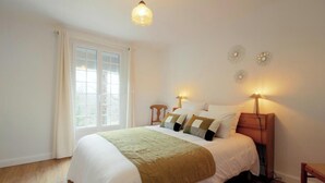 A bedroom with a bed, bedside lamps, a window, and a wall clock. - Gîte du Pitchouret - BELIN BELIET (BELIN BELIET)