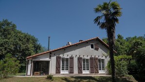 A two-story house with a sloped roof, large windows with shutters, and a small porch. - Gîte du Pitchouret - BELIN BELIET (BELIN BELIET)
