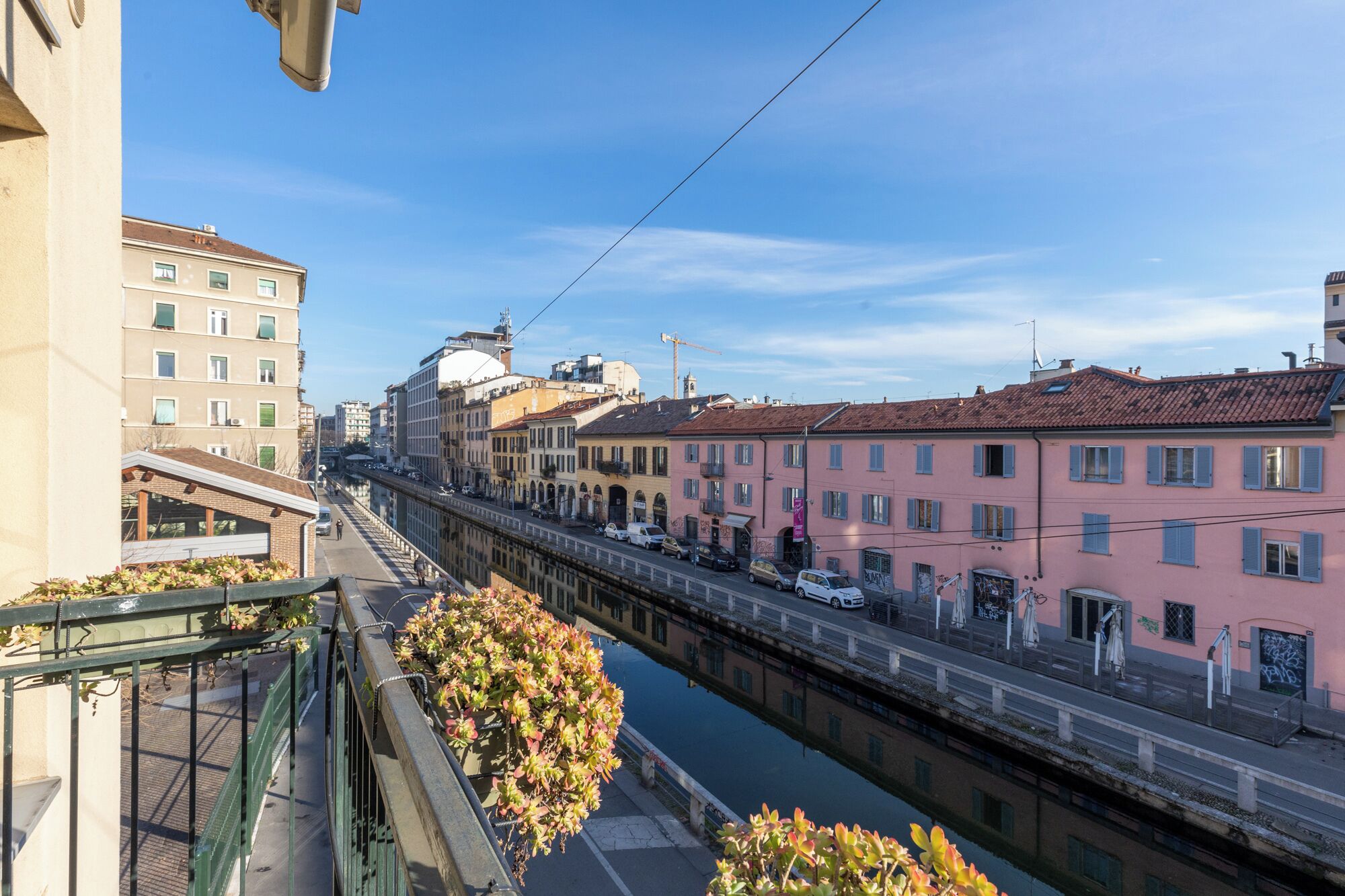 A canal with buildings on either side, a pedestrian bridge, and a clear sky.