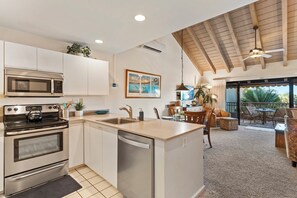Una cocina moderna con una isla central, electrodomésticos integrados y una zona de comedor con mobiliario exterior.