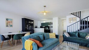 Un salon moderne avec un canapé, un coin repas et une cuisine en arrière-plan.