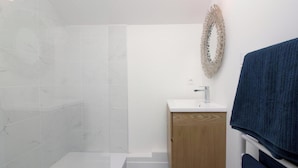 Une salle de bain avec une douche, un lavabo et un porte-serviettes.