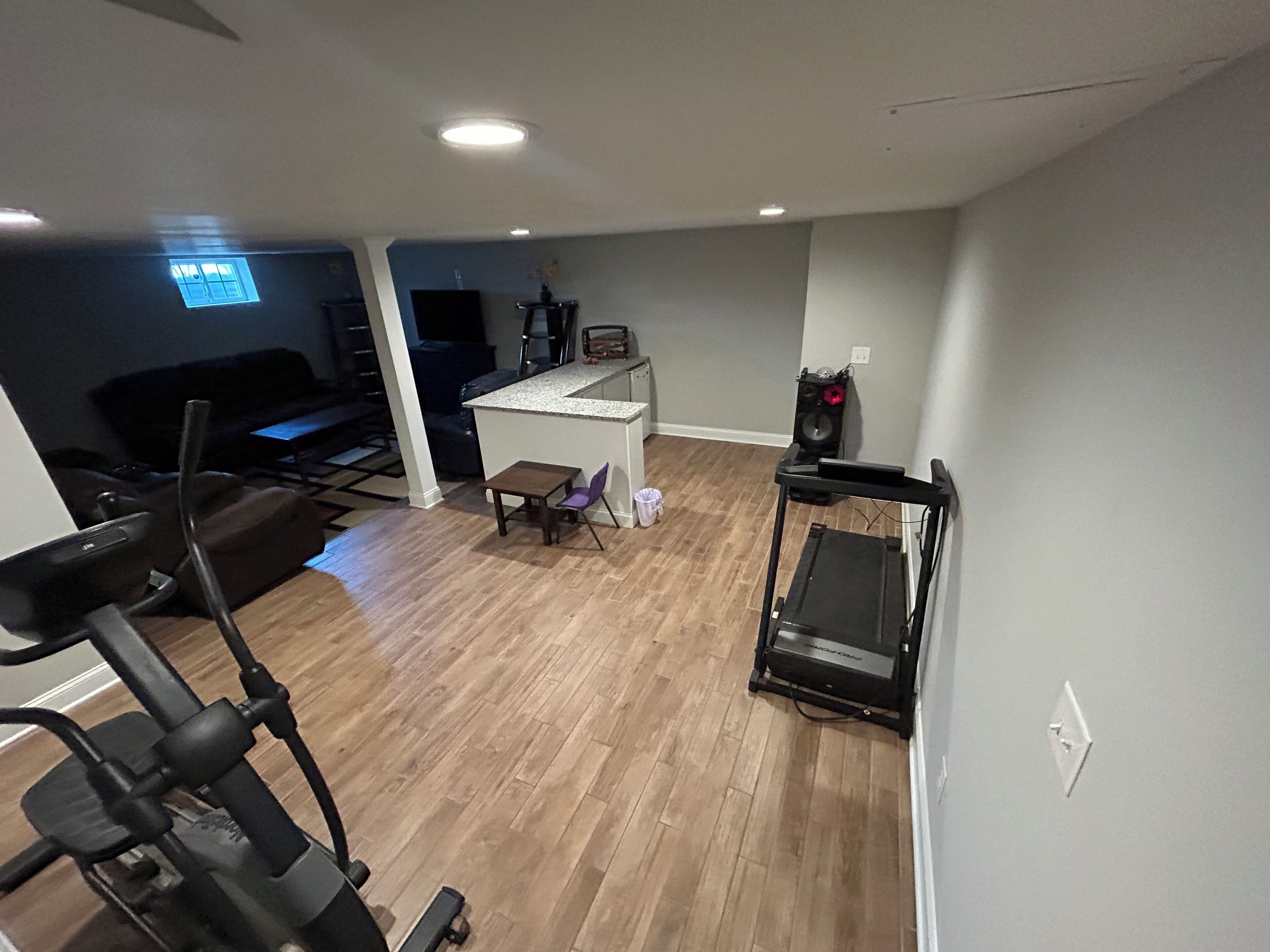 Et hjemmegym med træningsudstyr, et tekøkken og en opholdsstue med et fjernsyn.