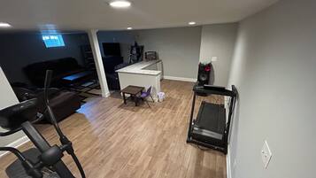 Et hjemmegym med træningsudstyr, et tekøkken og en opholdsstue med et fjernsyn.