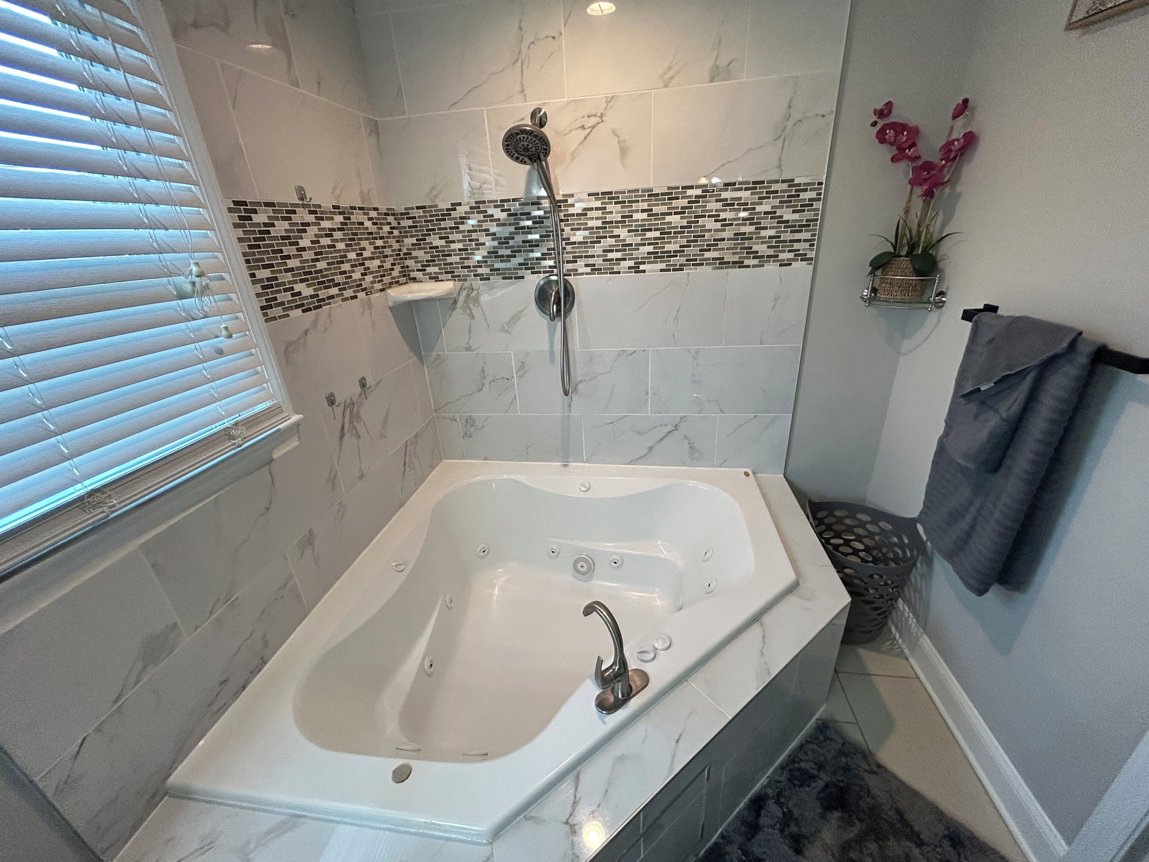 Un baño con una bañera independiente, un cabezal de ducha y una zona de ducha con azulejos.