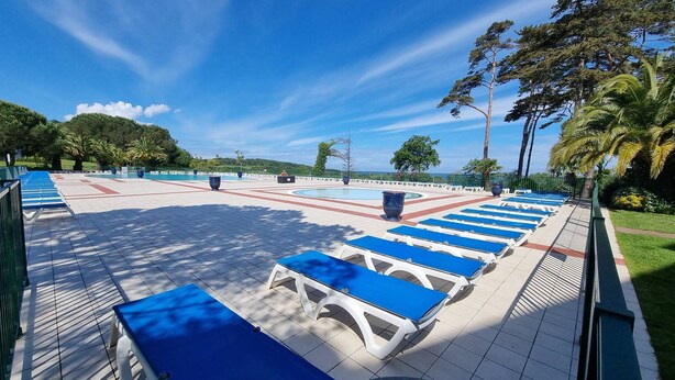 Área de piscina com espreguiçadeiras e um deck revestido de azulejos.