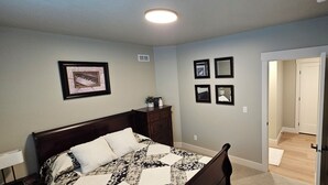 Un dormitorio con cama, cómoda y cuadros en la pared.