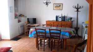 Een eethoek met een tafel, stoelen, een televisie en een kast.