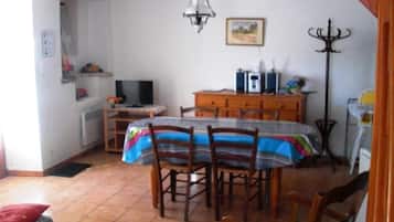 Zona de menjador amb taula i cadires, televisió i un armari.