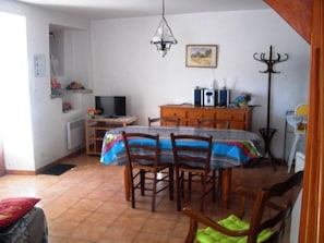 A dining area with a table and chairs, a television, and a cabinet. - La Terrasse Neuve in La Teissonnière (SAINT HILAIRE DE LAVIT)