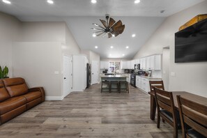Une cuisine moderne avec des meubles blancs, un îlot central et un ventilateur de plafond.