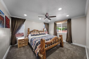 Une chambre avec un lit en bois, un ventilateur de plafond et une fenêtre avec des rideaux.