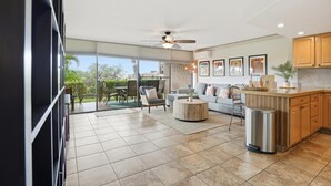 A modern kitchen with a dining area, large windows, and a ceiling fan. - 2 bedroom updated Kihei condo, AC, walk to beach, shops, & dining (Kihei)
