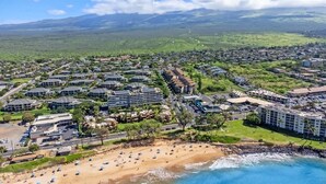 An aerial view of a coastal resort with multiple hotel buildings, a sandy beach, and a clear view of the ocean. - 2 bedroom updated Kihei condo, AC, walk to beach, shops, & dining (Kihei)
