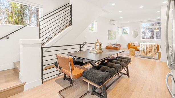 Et moderne interiør med trappe, spiseplads med bord og stole, sofa og bænk.