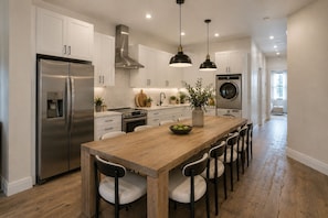A modern kitchen with stainless steel appliances, a wooden island, and pendant lighting. - Huge Luxury 3 Bedroom Duplex Apartment in Prime Location (New York)