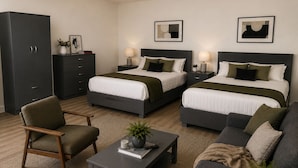 Ein Hotelzimmer mit zwei Betten, einem Schlafsofa, einem Sessel, einem kleinen Tisch und einem Schrank.
