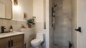 Ein Badezimmer mit Toilette, Dusche, Waschbecken und Spiegel.