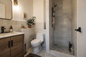 A bathroom with a toilet, a shower, a sink, and a mirror. - Huge Luxury 3 Bedroom Duplex Apartment in Prime Location (New York)