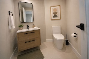 Une salle de bain moderne avec des toilettes, un lavabo et un miroir.