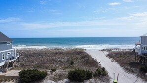 A beach house with a sandy path leading to the ocean, a clear view of the sea, and a wooden deck. - Charming 4-Bedroom Home with Ocean Views in Topsail Beach! (Topsail Beach)