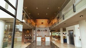 Een ruime lobby met een hoge plafond, een receptiebalie en een zithoek.