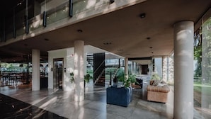 A spacious lobby with a high ceiling, large columns, and a staircase leading to upper levels. - Modern Rio Cuarto Retreat: Spa, Indoor Pool | 10 Min Drive to IAH Airport (Río Cuarto)