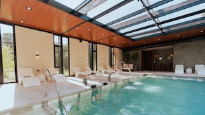 A swimming pool with lounge chairs and a glass ceiling. - Modern Rio Cuarto Retreat: Spa, Indoor Pool | 10 Min Drive to IAH Airport (Río Cuarto)