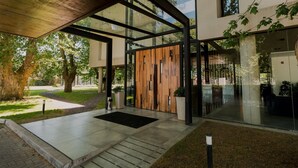 Entrada d'un edifici modern amb portes de vidre, una paret de fusta i una zona de jardí.