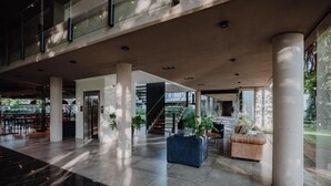 Un vestíbul espaiós amb un sostre alt, columnes grans i una escala que condueix a plantes superiors.