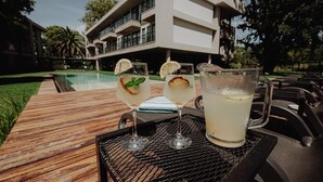Ein modernes Gebäude mit Schwimmbad, zwei Gläsern mit einem Getränk und Zitronenscheiben sowie einer Karaffe auf einem Tisch.