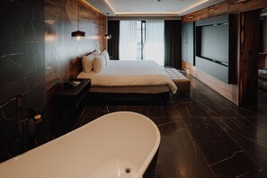 Et moderne hotelværelse med en stor seng, badekar og udsigt over byen.