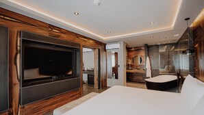 A modern hotel room with a large flat-screen TV, a bed, a bathroom with a bathtub, and a mirror. - Elegant Room Designed for Serenity Near Sarmiento Park – Free Breakfast (Río Cuarto)