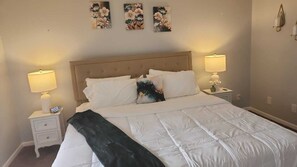 A bedroom with a bed, two bedside tables, a nightstand, a clock, and wall art. - 2-BR Apt in Deerfield Beach with AC, Free wifi and Free parking near Golf Course (Deerfield Beach)