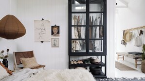 A room with a bed, a chair, a black cabinet with clothes, and a bench. - open plan contemporary barn in the heart of Daylesford (Daylesford)