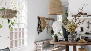 A bright, white interior with a high ceiling, a round wooden table, a hanging basket with plants, and a white bust sculpture. - open plan contemporary barn in the heart of Daylesford (Daylesford)