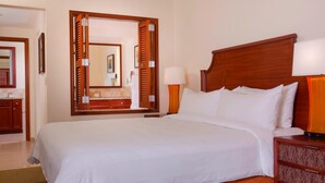 Ein Hotelzimmer mit einem großen Bett, einem Holz-Kopfteil, einem Nachttisch mit Lampe und einem Spiegel mit Holzrahmen.